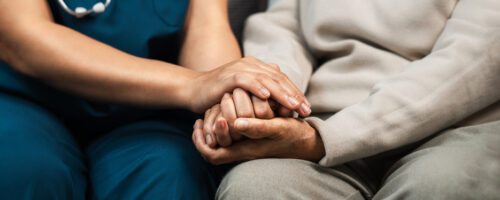 A female nurse caregiver holds hands to encourage and comfort an elderly woman. For care and trust in nursing homes for people of retirement age Caregiver helping elderly woman provides medical advice