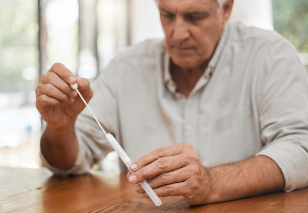 Mature man, covid pcr test or swab for mouth or nose in home kit, house or living room for healthcare insurance or medical virus disease. Zoom, hands or antigen covid 19 check for patient in lockdown